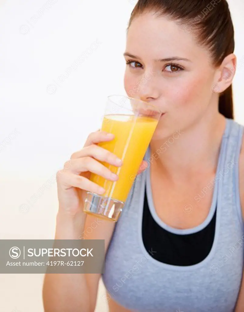 Healthy young woman drinking a glass of fresh orange juice