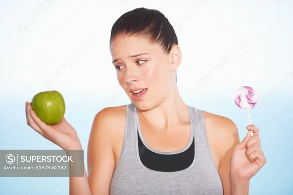 An attractive young woman deciding between an apple or some candy