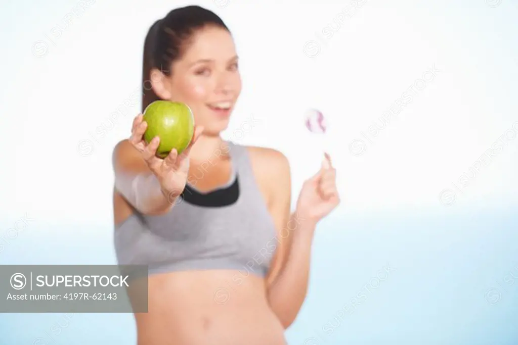 An attractive young woman choosing an apple over some candy