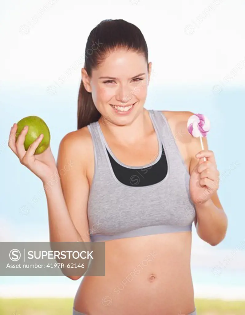 An attractive young woman deciding on an apple over some candy