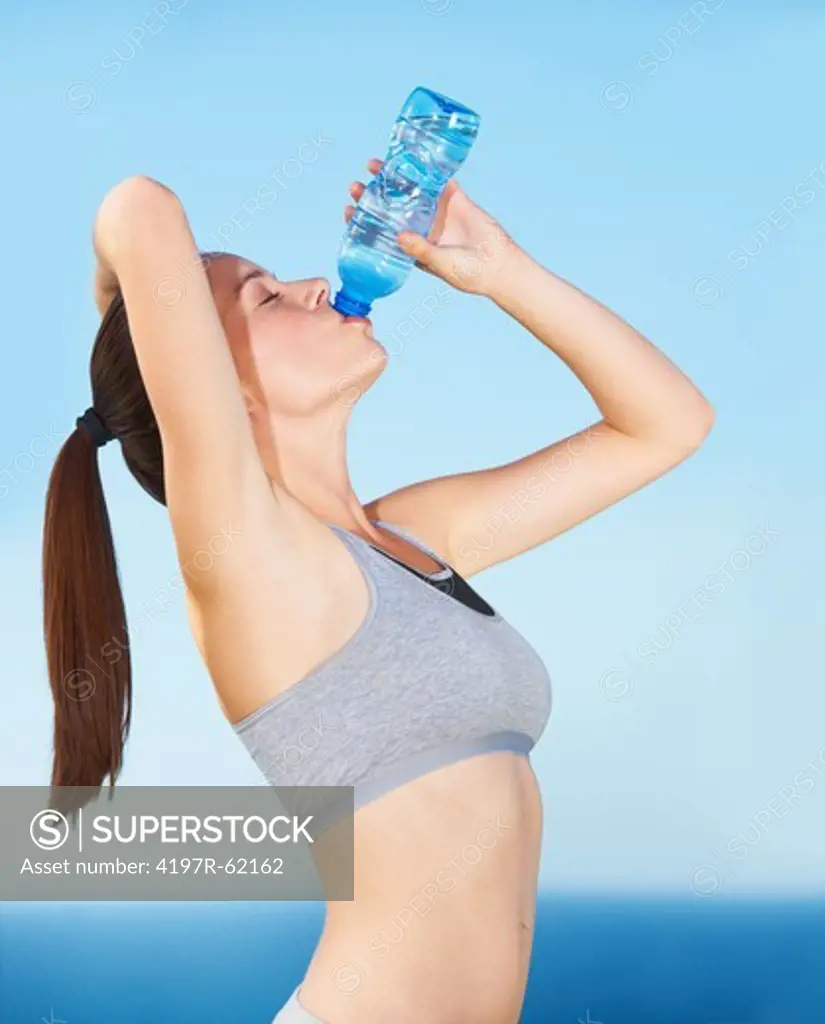 An attractive young woman drinking a bottle of water