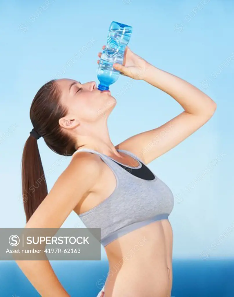 A beautiful young woman drinking from a bottle of water