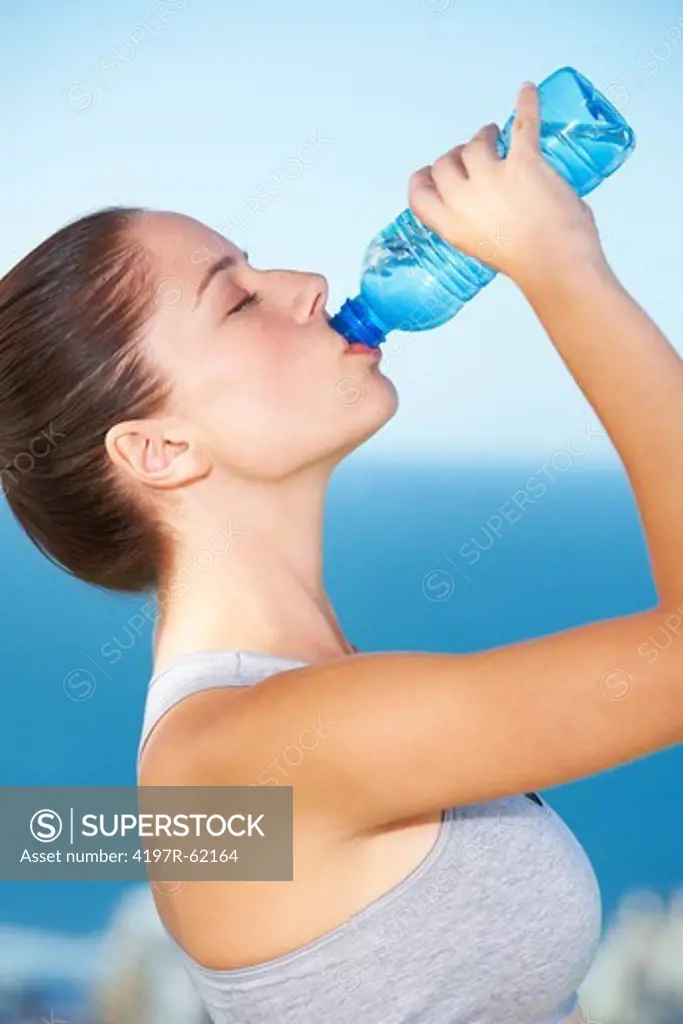 An attractive young woman drinking from a bottle of water