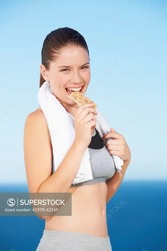 A beautiful young woman biting a protein bar