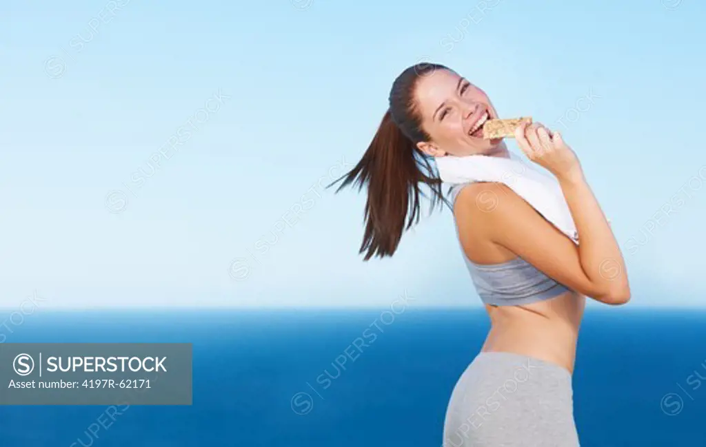 A pretty young woman taking a bite from a protein bar