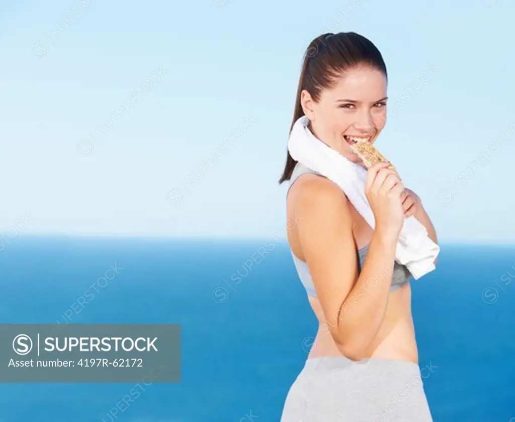 A pretty young woman biting a protein bar