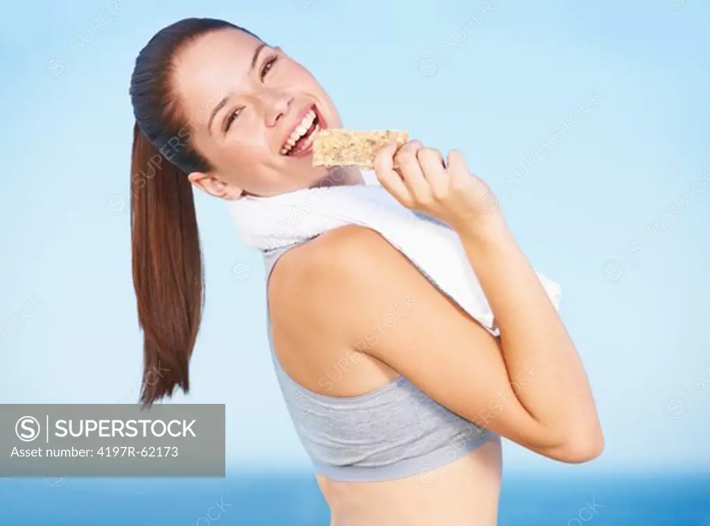 A pretty young woman eating a protein bar