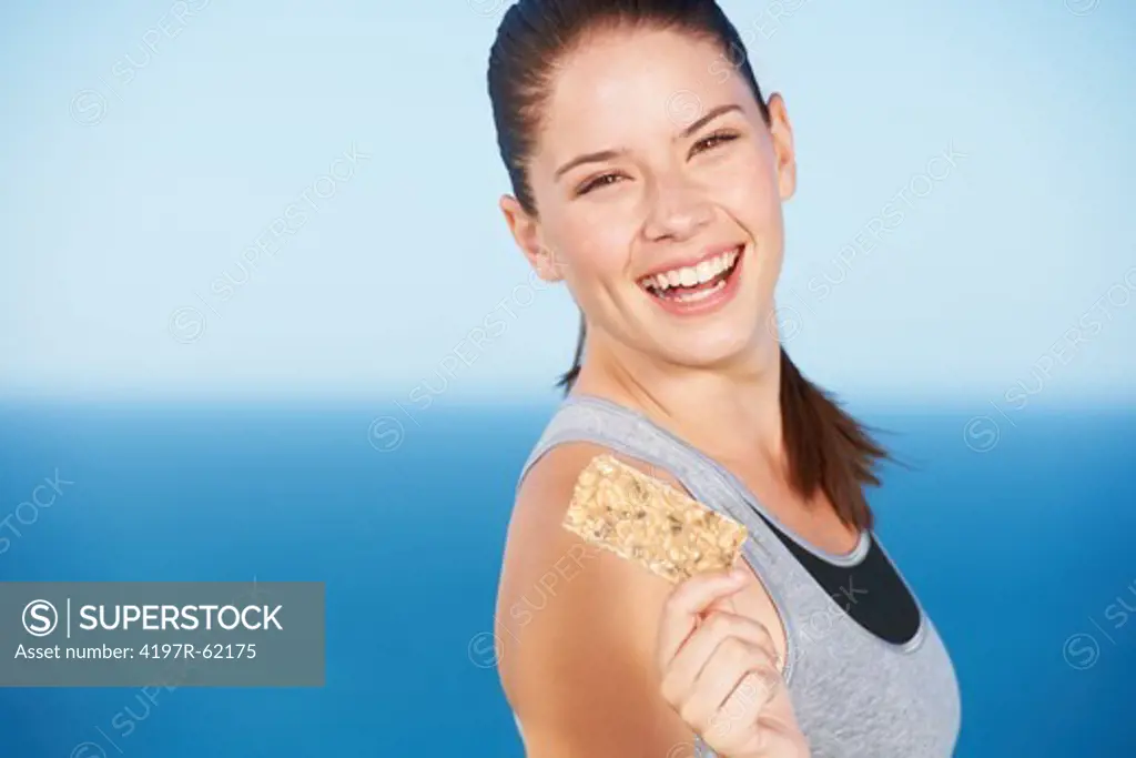 A pretty young woman holding a protein bar
