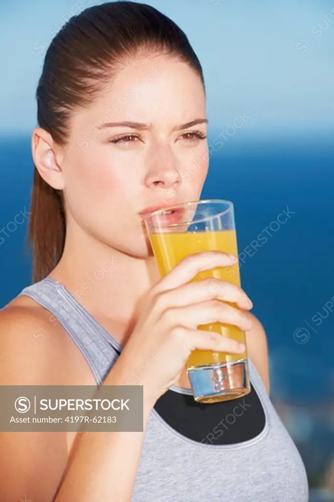 A beautiful young woman drinking orange juice