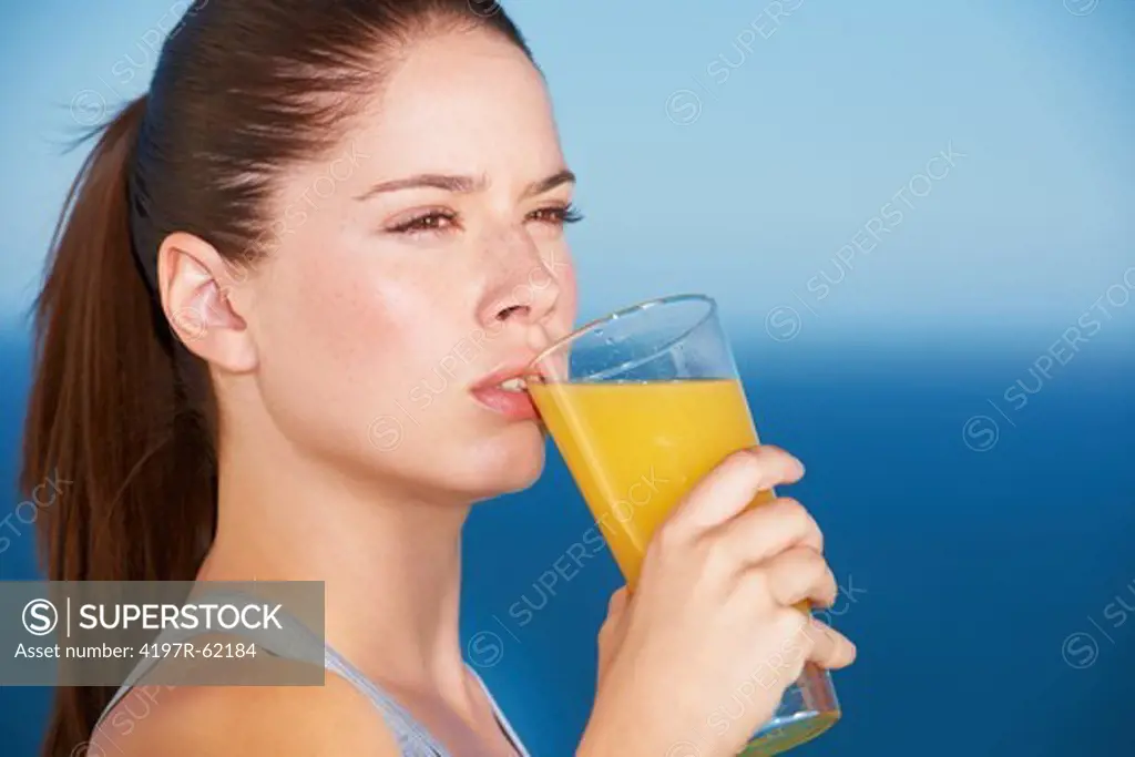 An attractive young woman drinking orange juice
