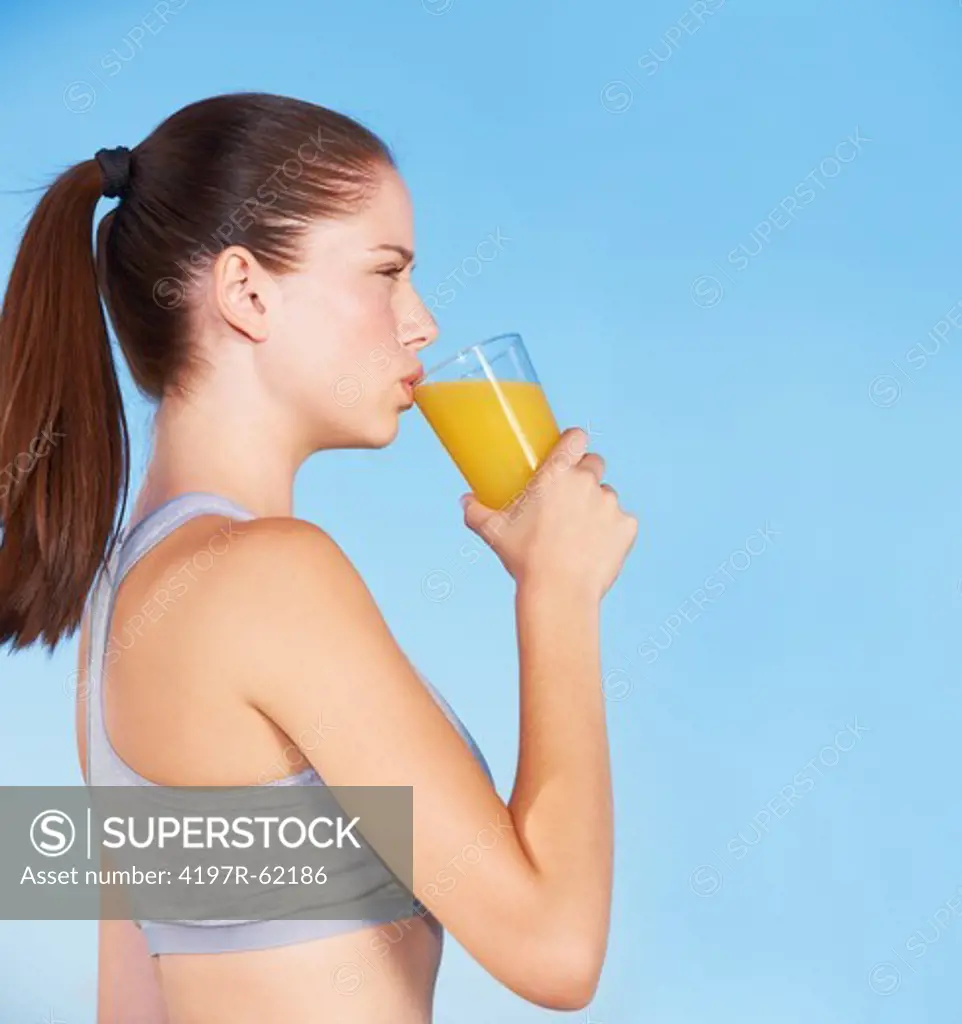 An attractive young woman drinking orange juice from a glass