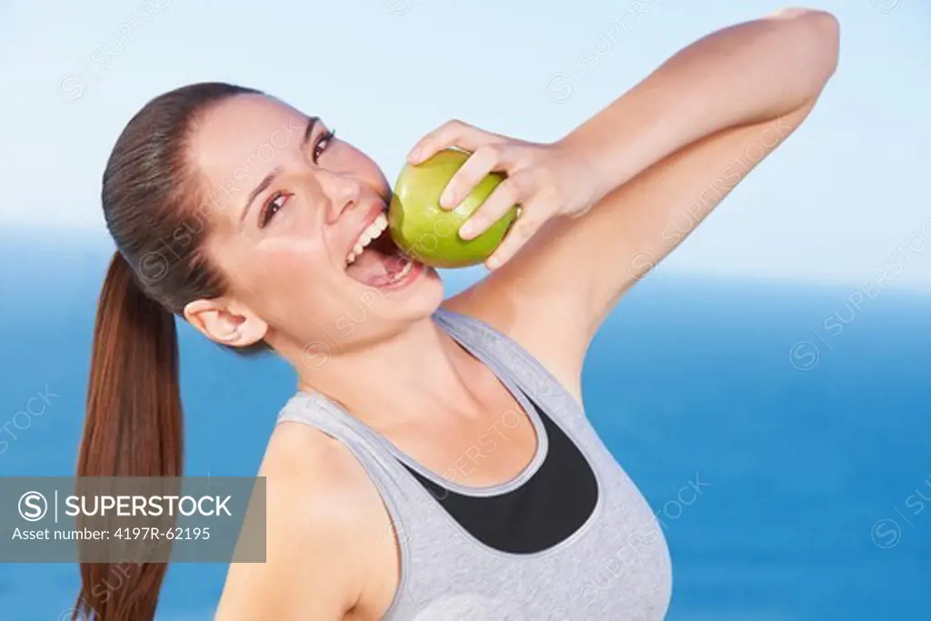 An attractive young woman taking a bite from a green apple