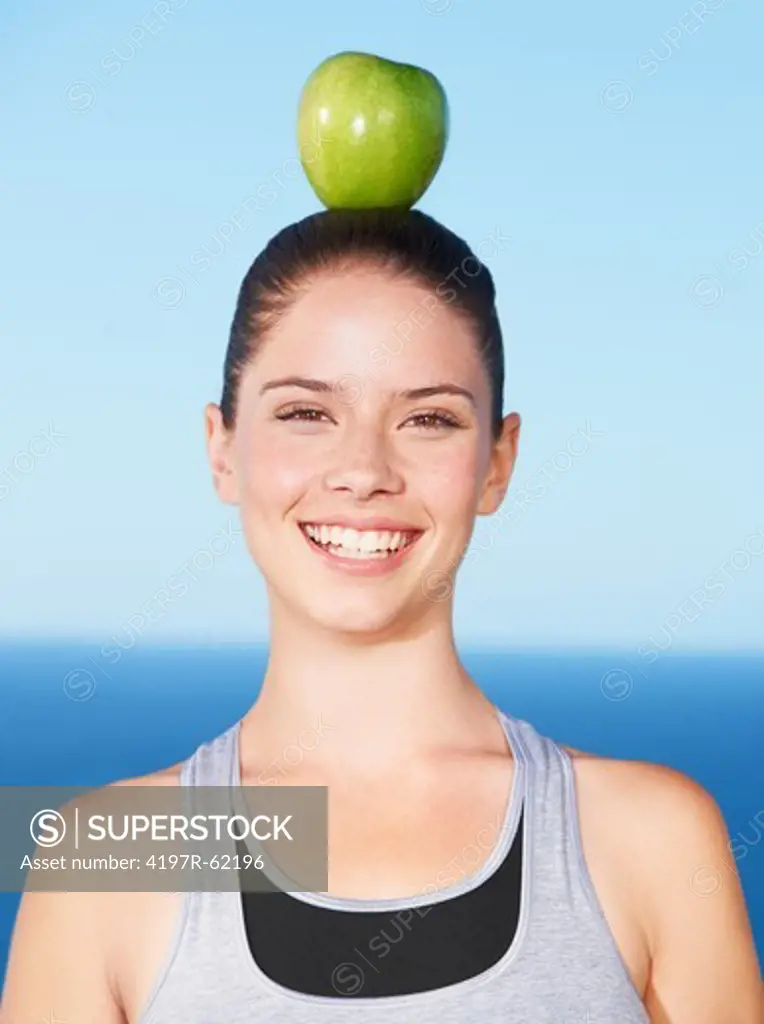 An attractive young woman with a green apple on her head