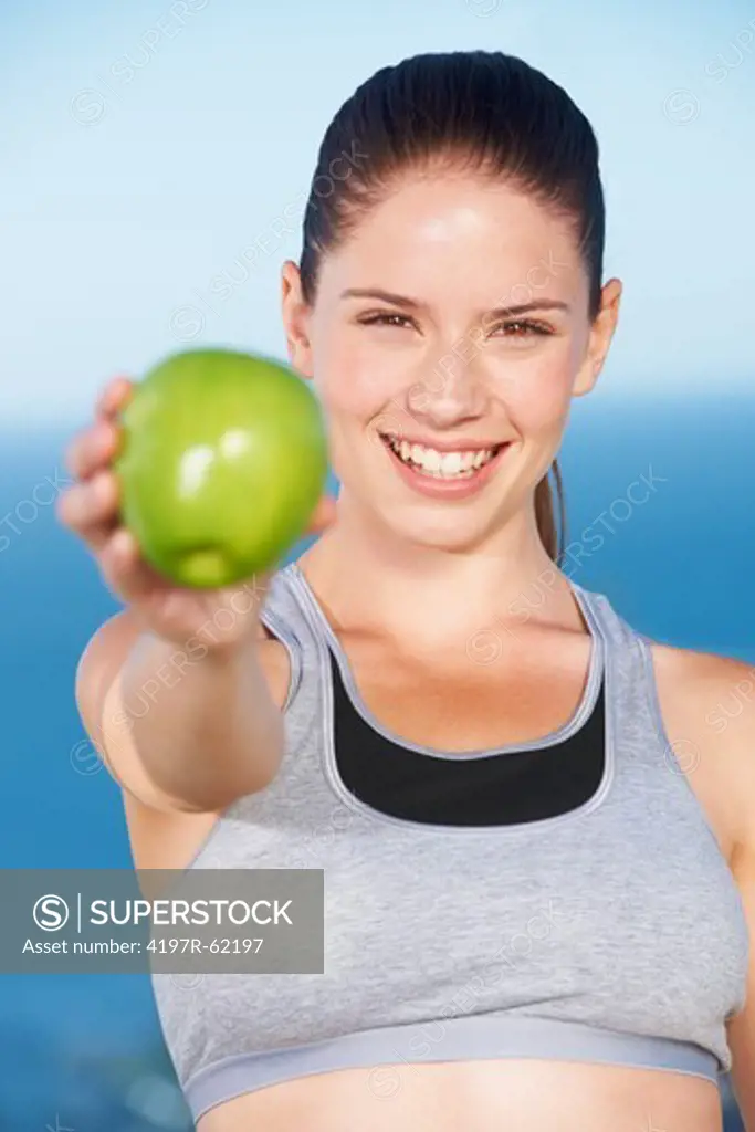 An attractive young woman holding up a green apple toward the camera