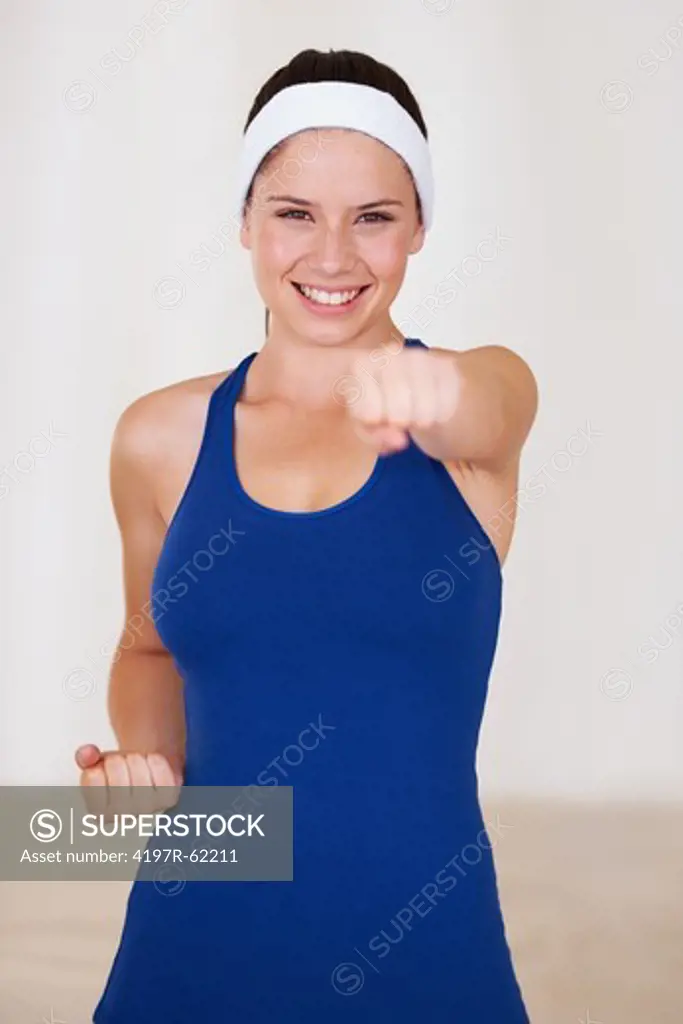 Fit young woman punching towards you with a smile