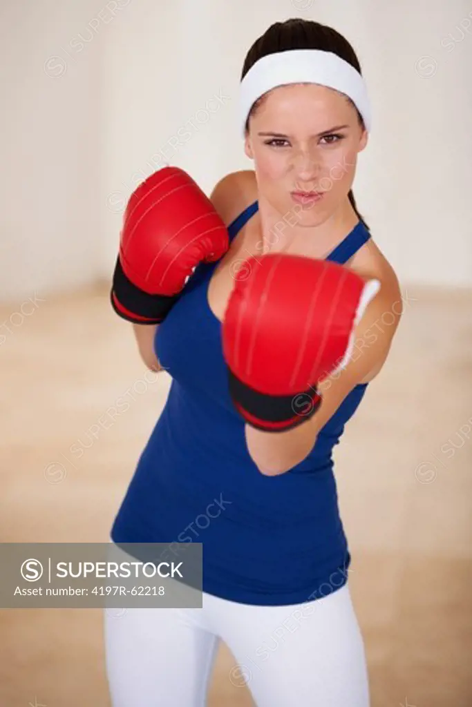 Serious young woman wearing lightweight boxing gloves for a workout and punching