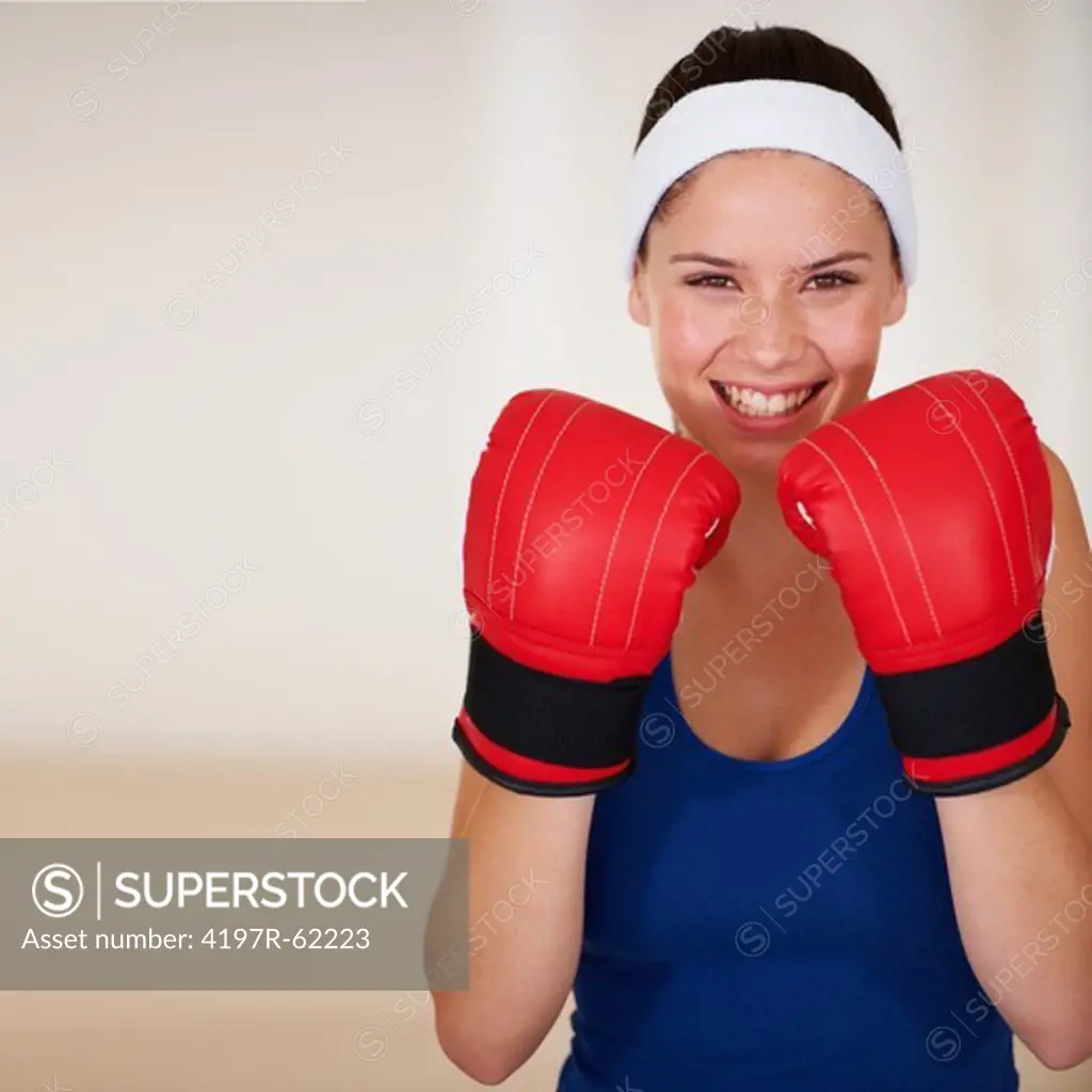 Smiling young woman wearing lightweight boxing gloves for a workout