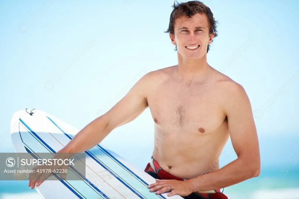 Portrait of a young surfer with his surfboard at the beach