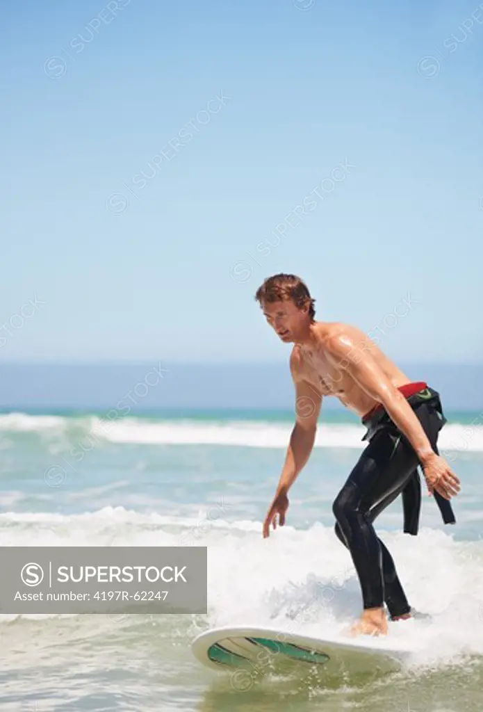 A young male surfer standing on his surfboard