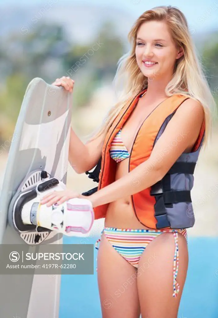 Pretty young wakeboarder holding her board and wearing a life jacket