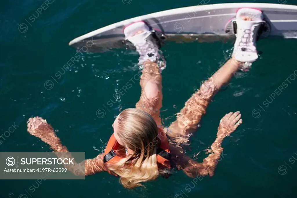 Rear view of a young female wakeboarder floating in the lake