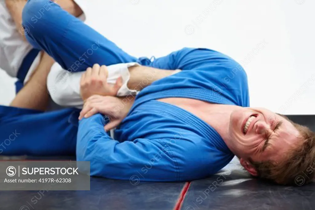 Shot of a young martial artist in pain while sparring with another in a dojo