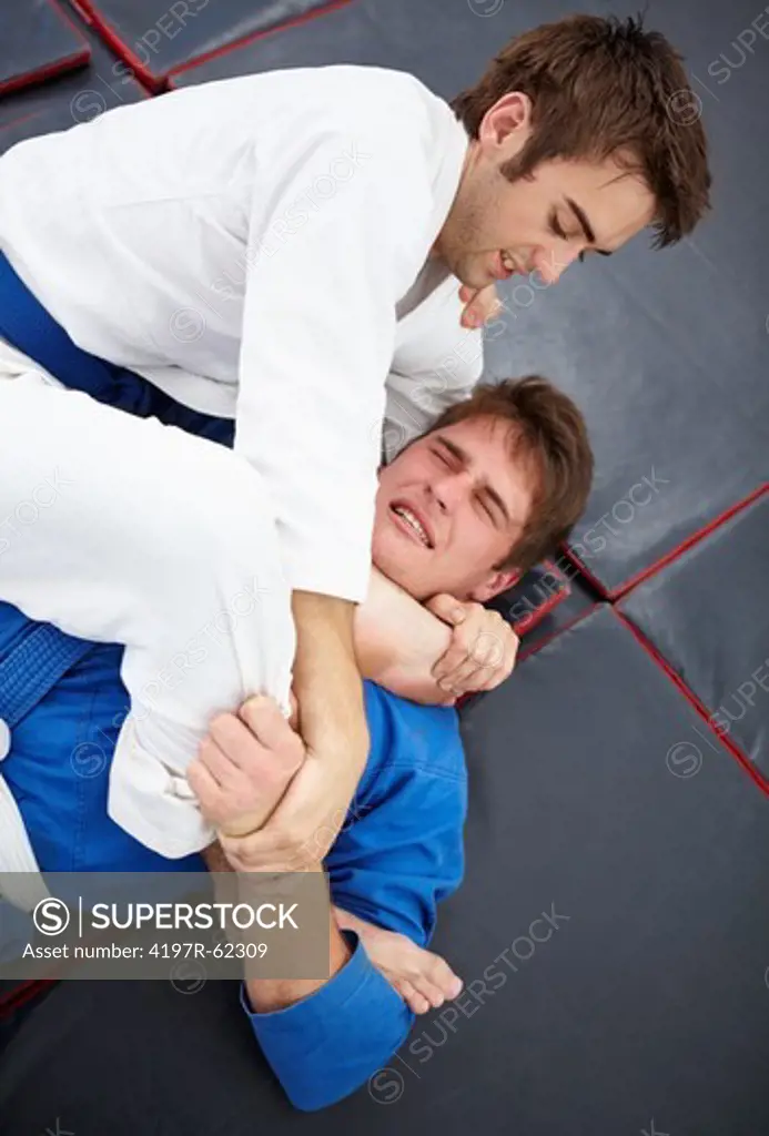 Shot of two young martial artists sparring in the dojo with one choking out the other