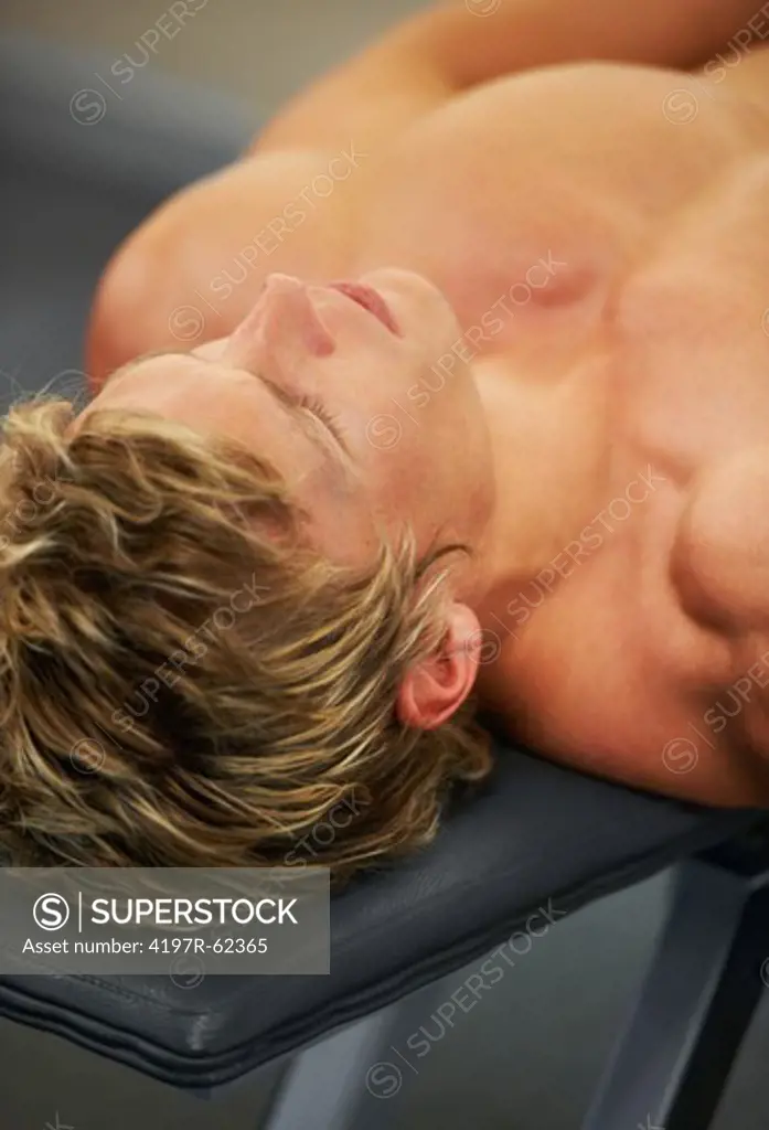 A young man lying on the bench press at the gym