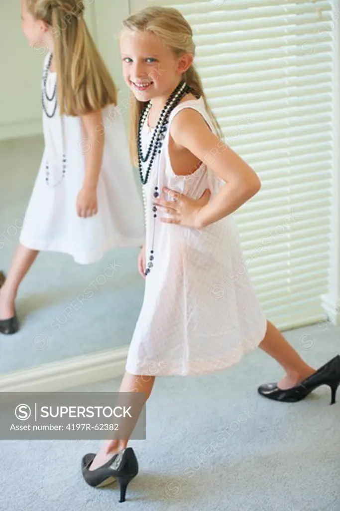 A cute young girl playing dress up and wearing her mother's high heels