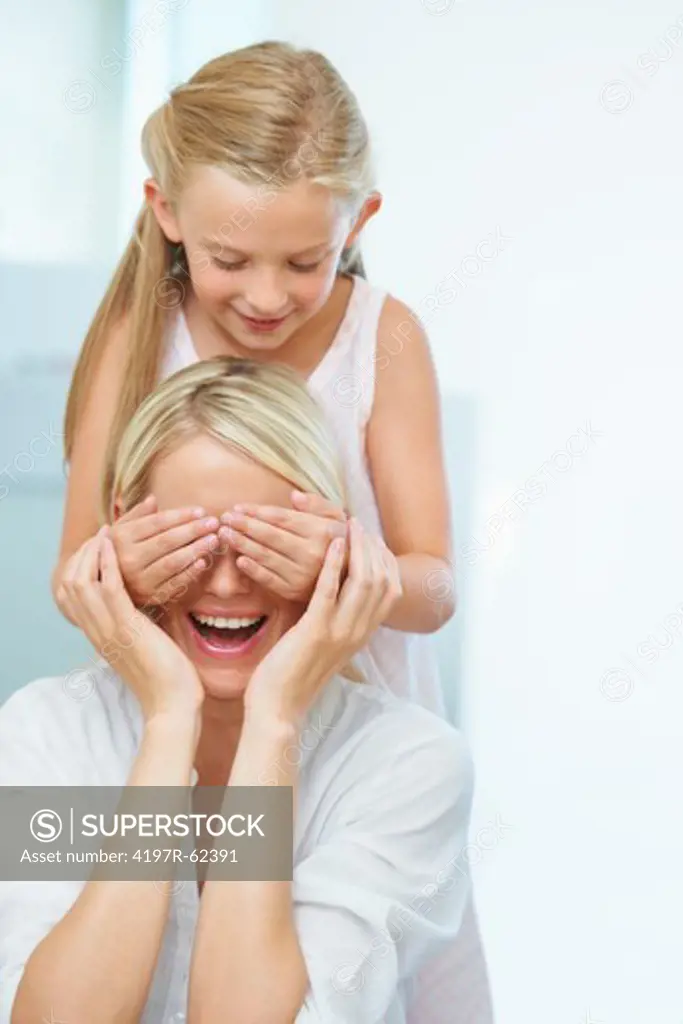 A cute young girl surprising her mother by covering her eyes
