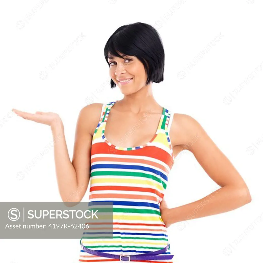 Casual young woman smiling and gesturing towards copyspace while standing against a white background