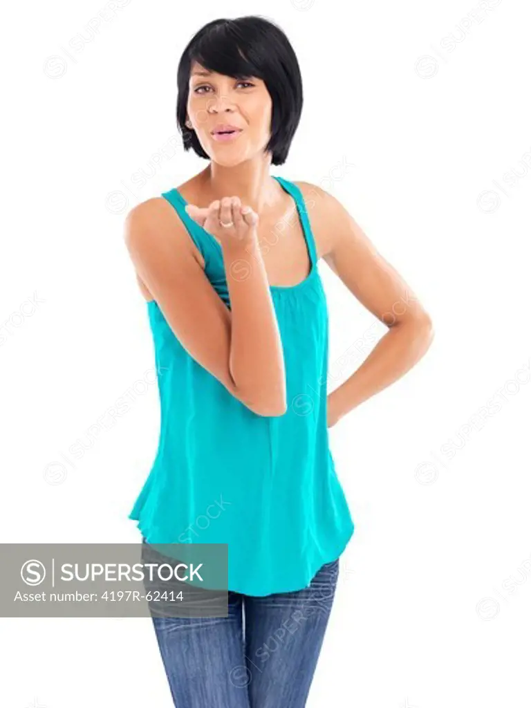 Casual young woman blowing a kiss while standing against a white background