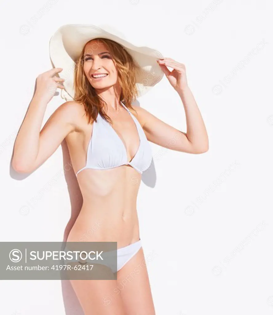 Stylish young woman smiling while wearing a white bikini and a sunhat