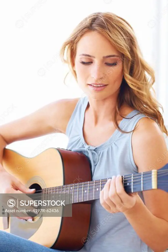 Pretty young woman holding her guitar and playing some music