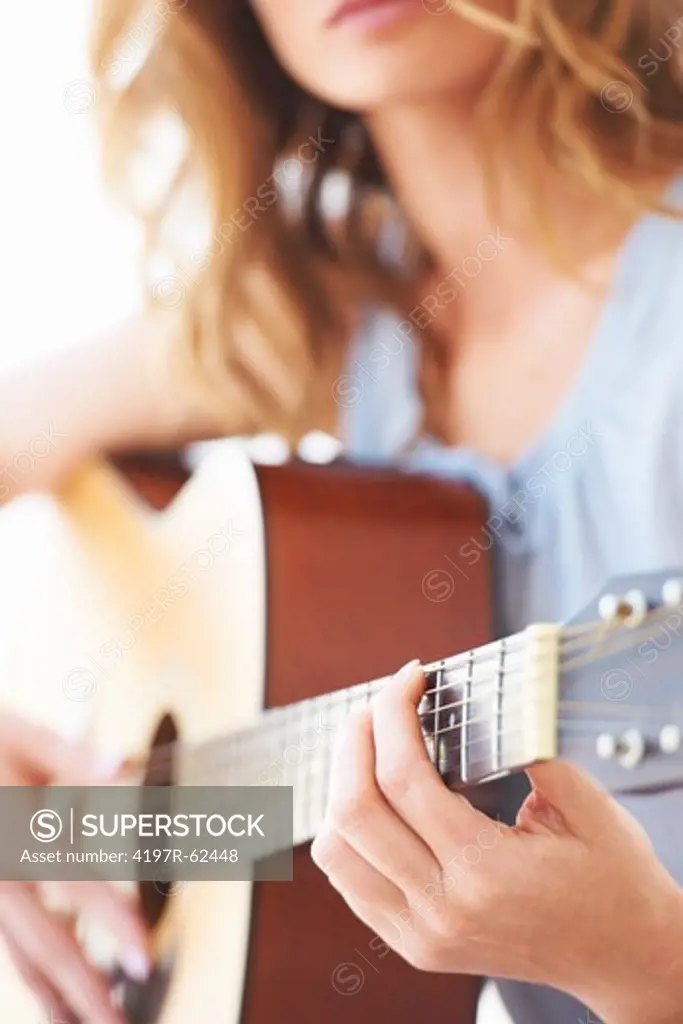 Cropped view of a young woman playing her guitar