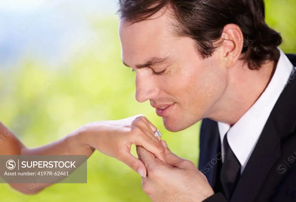 A husband kissing his wife's hand at their wedding reception
