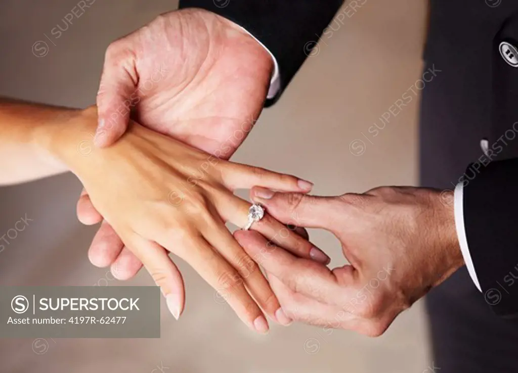 Cropped image of a husband placing the ring on his wife's finger