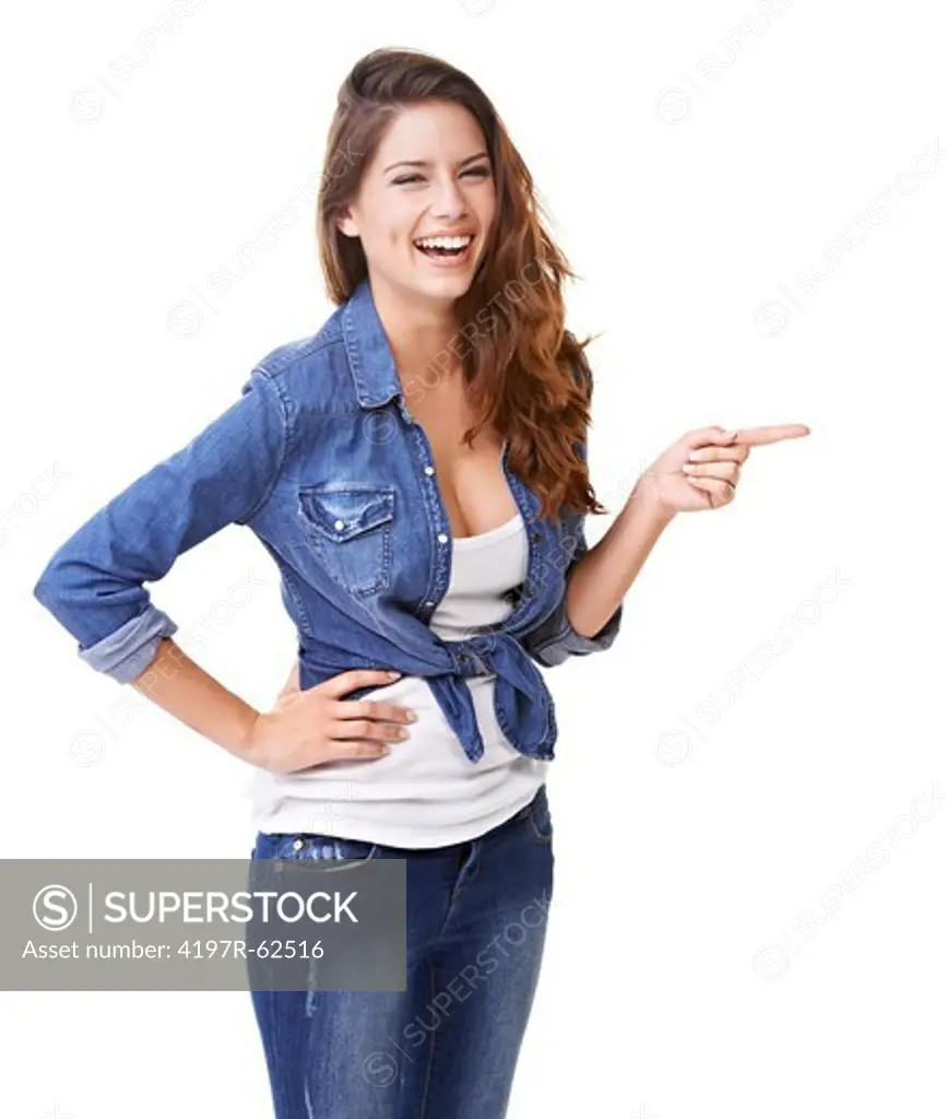Studio portrait of an attractive young brunette woman laughing and pointing out of frame isolated on white