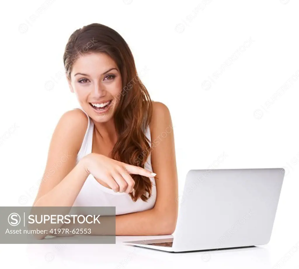 Shot of an attractive young woman pointing at a laptop and smiling at the camera