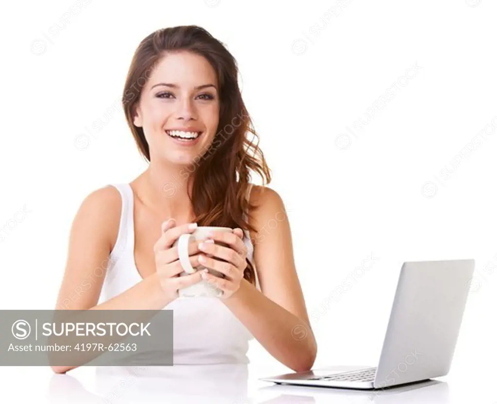 Studio shot of an attractive young woman enjoying a cup of coffe while working on a laptop