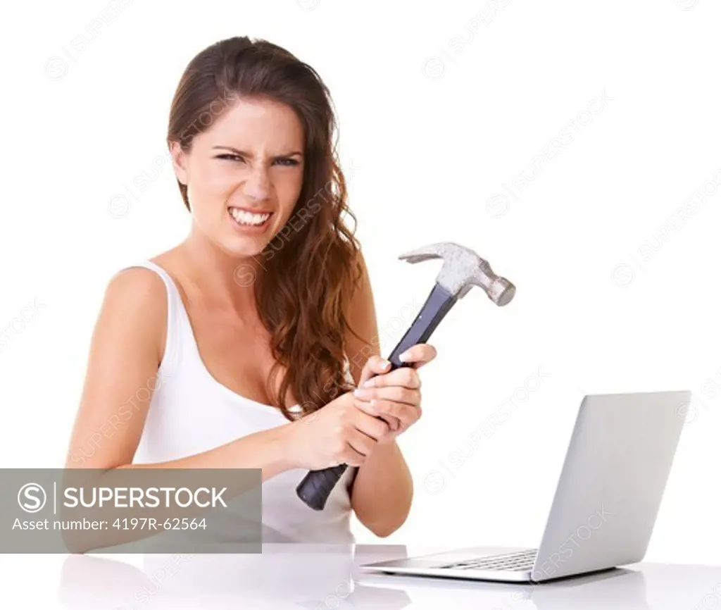 Studio shot of a frustrated-looking young woman about to smash a laptop with a hammer