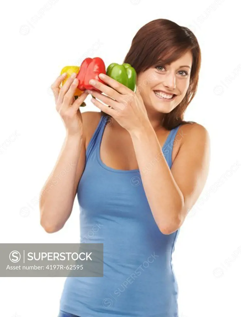 Studio shot of a young woman holding up colourful peppers isolated on white