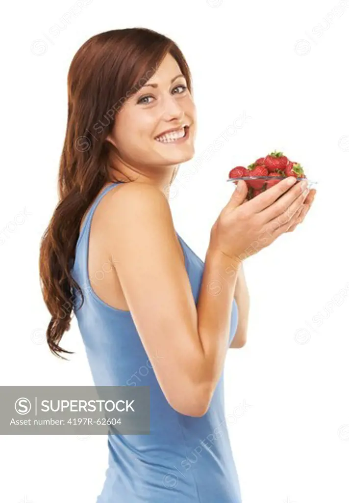 Sideways studio portrait of an attractive woman holding a bowl full of strawberries isolated on white