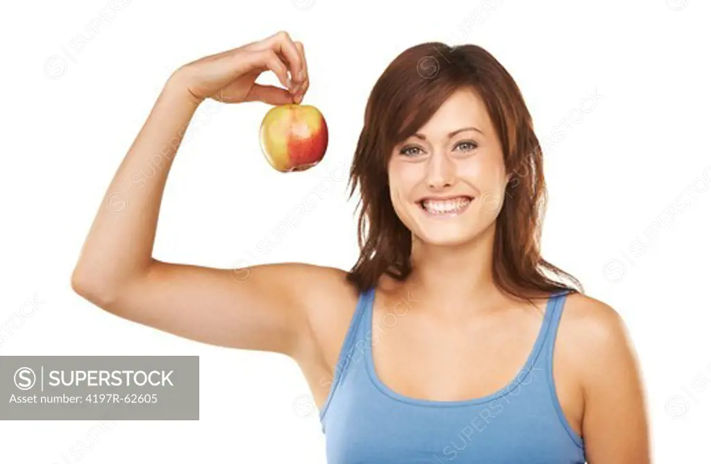 Studio portrait of a smiling young woman dangling a single apple from her raised arm isolated on white