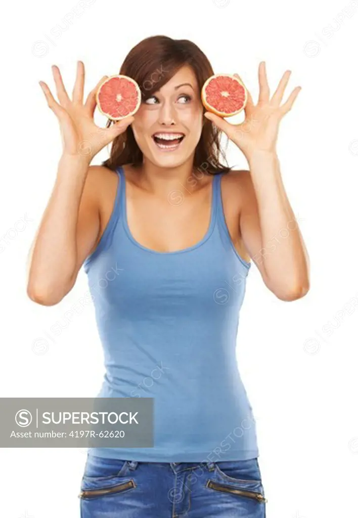 Playful studio portrait of a young woman holding up grapefruit sections next to her face isolated on white