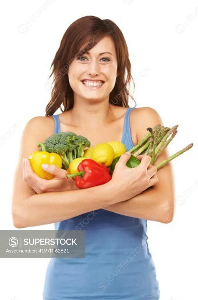 Studio shot of a young woman holding a variety of vegetables and fruit in her arms isolated on white
