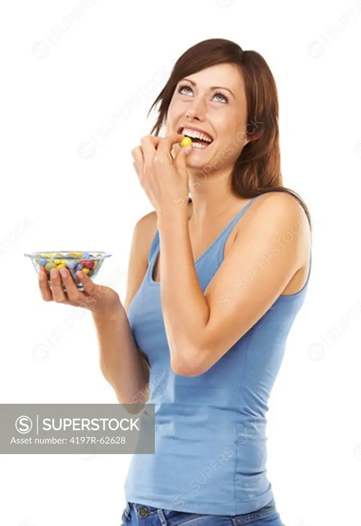 Studio shot of a young woman holding a bowl full of jellybeans in front of her isolated on white