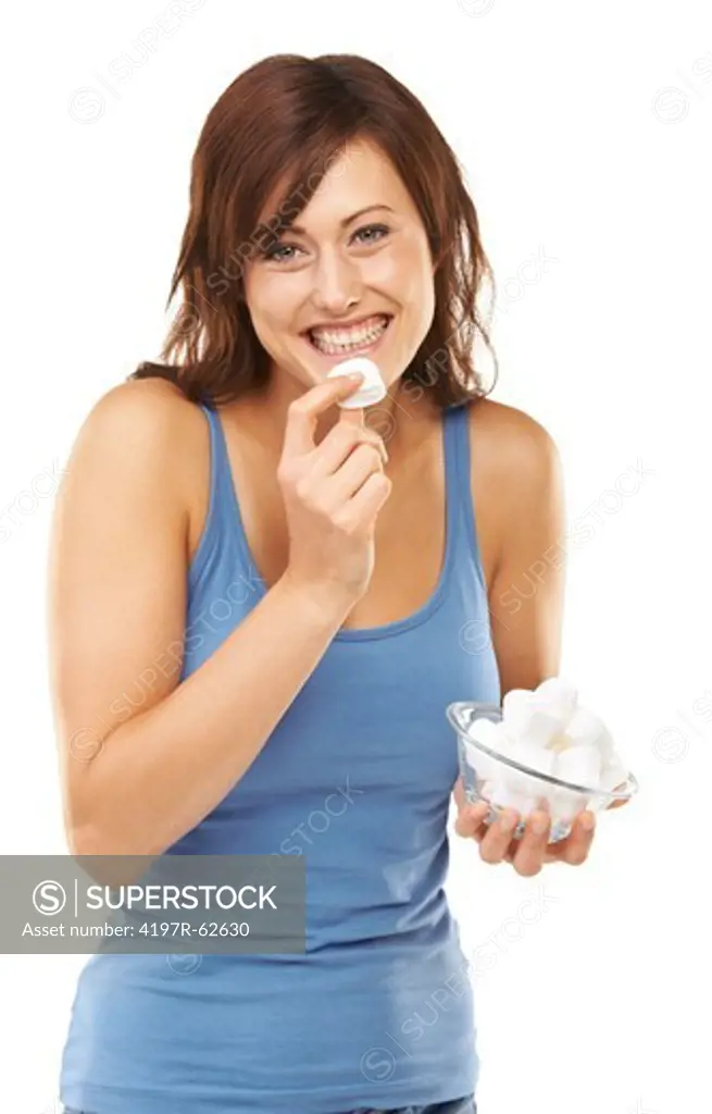 Playful studio portrait of a young woman eating from a bowl full of marshmellows isolated on white