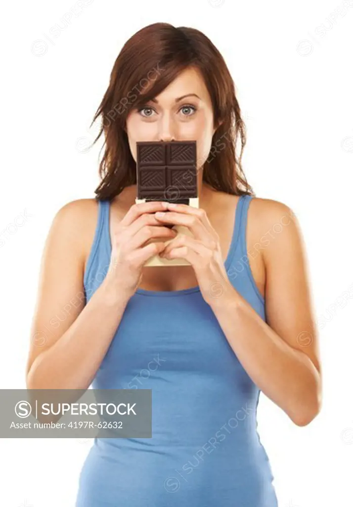 Studio shot of a young woman holding a large bar of chocolate in front her mouth isolated on white