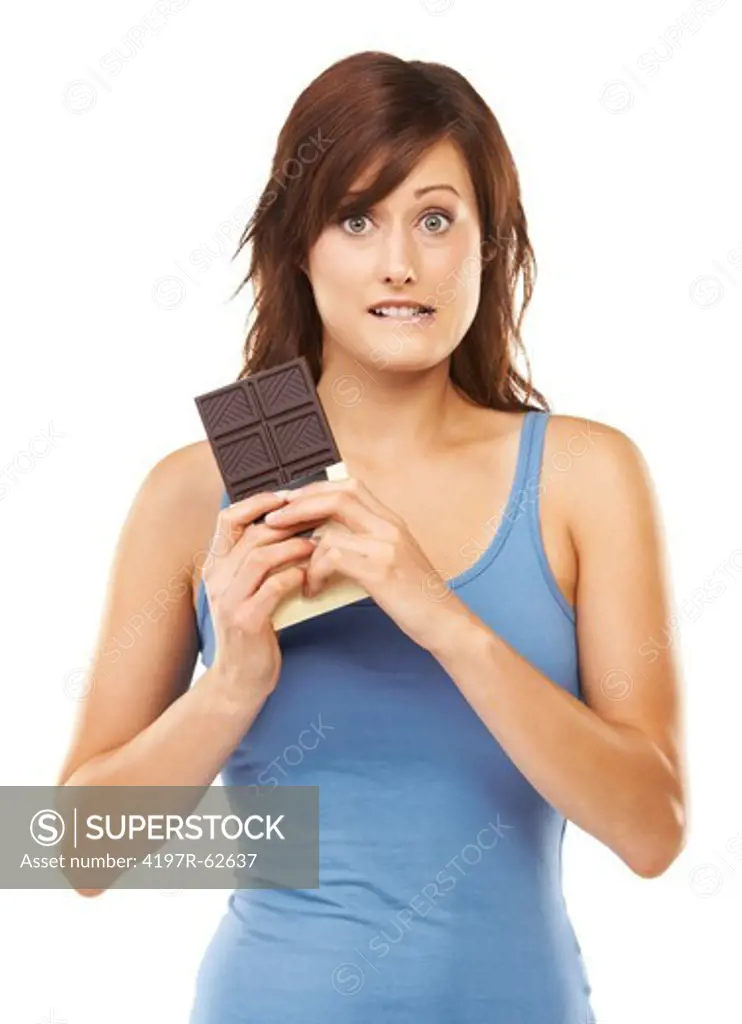 Studio portrait of a tempted-looking young woman holding a huge bar of chocolate isolated on white